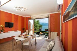 un soggiorno con pareti arancioni, tavolo e sedie di Casa Vacanze La Nautica a Baveno
