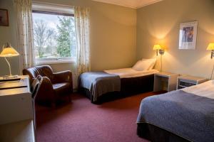 um quarto de hotel com duas camas e uma cadeira e uma janela em Wärs - Wärdshuset på Dal em Mellerud
