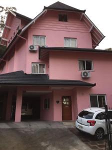 a pink house with a car parked in front of it at Pousada Beija Flor Centro in Gramado +16 photos