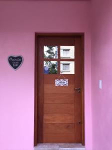 a wooden door in a pink room with a window at Pousada Beija Flor Centro in Gramado