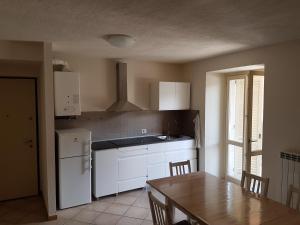une cuisine avec des placards blancs et une table avec une table dans l'établissement residenza la roggia, à Varallo