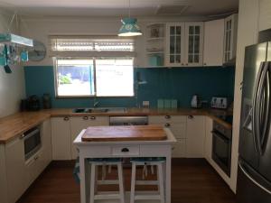 a kitchen with white cabinets and a wooden counter top at Aqua Shack Jurien Bay in Jurien Bay