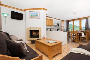 sala de estar con sofá y chimenea en Madame Vacances Les Chalets du Praz, en La Plagne