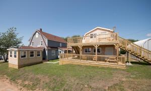 a house with a large deck on the yard at The Archie & Isidore Hotel in Chéticamp