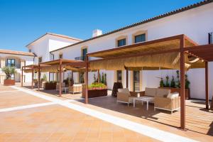a patio with chairs and umbrellas in front of a building at Iberostar Selection Andalucia Playa in Chiclana de la Frontera