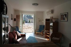 a living room with a couch and chairs and an open door at Maison Sous les Platanes in Saint-Pantaléon-les-Vignes