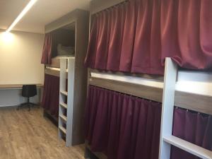 Habitación con 2 literas y cortinas rojas. en Auberge du Guintzet, en Fribourg