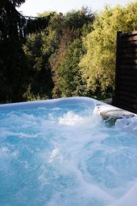 a hot tub filled with blue water next to trees at Vertes Feuilles in Saint-Sauveur