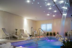 a spa room with a swimming pool with chairs and a swimming pool at Turin Palace Hotel in Turin