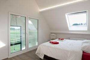 een slaapkamer met een wit bed en 2 ramen bij gastenverblijf 't Baertshof in Zonnebeke