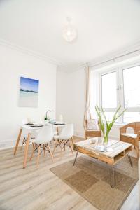 una sala de estar blanca con mesa y sillas en Modern Central Apartment en Aberdeen