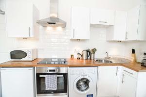 a white kitchen with a microwave and a dishwasher at Modern Central Apartment in Aberdeen