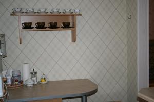 a kitchen with a table and a shelf with cups at Yulia Apartment in Narva