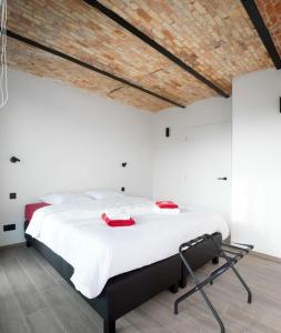 um quarto com uma grande cama branca com alças vermelhas em gastenverblijf 't Baertshof em Zonnebeke
