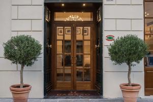 two potted trees in pots in front of a door at Hotel Damaso in Rome