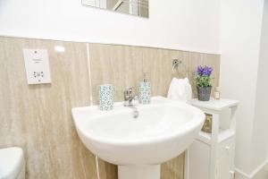 a bathroom with a white sink and a toilet at Modern Central Apartment in Aberdeen