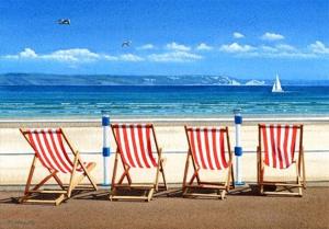 un grupo de cuatro sillas sentadas en una playa en Sea breeze holiday apartment, en Weymouth