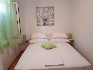 - un lit blanc dans une chambre avec une photo de fleurs sur le mur dans l'établissement Apartment Tempera, à Povlja