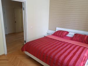a red bed with red pillows in a bedroom at Vilhelm's Apartment in Klaipėda