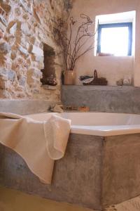 La salle de bains en pierre est pourvue d'une baignoire et d'une fenêtre. dans l'établissement I Freschi, à San Bartolomeo al Mare