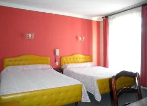 two beds in a room with red walls at La Pierre Lys in Quillan