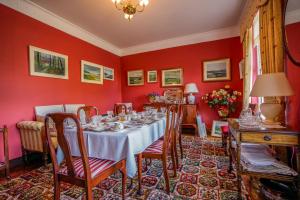a dining room with a table and red walls at Tattykeel House in Omagh