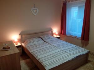 a bedroom with a bed with two lamps and a window at Éva vendégház Guesthouse in Hajdúszoboszló