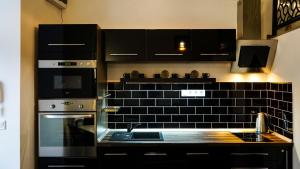 a kitchen with a stove top oven and black tiles at DownTown DeLuxe Apartment in Eger +21 photos