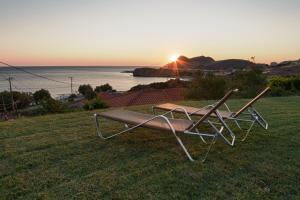 a bench sitting on the grass with the sunset in the background at Sunset Hotel in Agios Ioannis Kaspaka