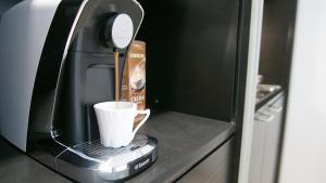 eine Kaffeemaschine mit einer Tasse auf der Theke in der Unterkunft Laguna Apartment in Wien