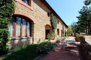 un bâtiment en briques avec des tables et des chaises sur une terrasse dans l'établissement Agriturismo Antico Borgo Poggitazzi, à Loro Ciuffenna