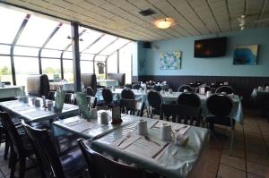 ein Esszimmer mit Tischen, Stühlen und Fenstern in der Unterkunft Hotel L'Express in Longueuil
