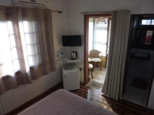 1 dormitorio con 1 cama y 1 habitación con TV en Pousada Casa Amarela, en Canela