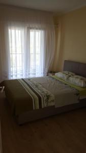 a bedroom with a bed and a window with curtains at Apartment Vujačić in Bar