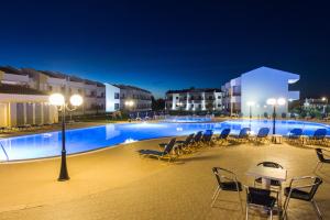 a swimming pool with chairs and tables at night at Stemma Hotel in Sidari