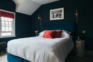 a blue bedroom with a large bed with red pillows at The Porterhouse grill & rooms in Oxford