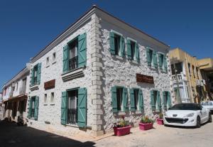 un bâtiment avec des volets verts et une voiture garée devant dans l'établissement Alya Mou Butik Hotel, à Çeşme