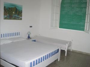 トッレ・ラピッロにあるVillino rossoの白い部屋(ベッド2台、緑の窓付)