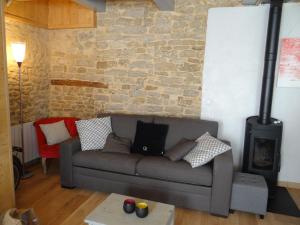 a living room with a couch and a brick wall at Maison Rétaise près de la Plage in Saint-Clément-des-Baleines
