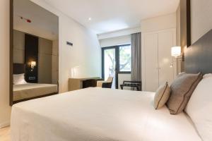 sypialnia z dużym białym łóżkiem i oknem w obiekcie Hotel Capital Lisboa w Lizbonie