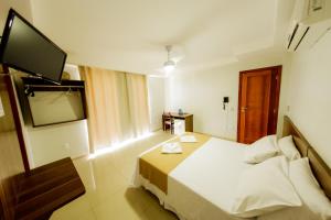 a hotel room with a bed and a flat screen tv at Sollar hotel in Aracruz