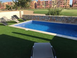 una piscina en un patio con sillas en el césped en Villa Mar menor Golf, en Torre-Pacheco