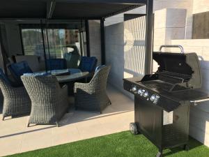 a grill on a patio with chairs and a table at Villa Mar menor Golf in Torre-Pacheco