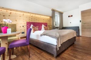 a bedroom with a bed and a table and purple chairs at Hotel Talblick in Saalbach Hinterglemm