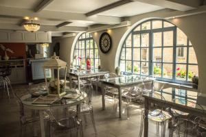 a room with tables and chairs and a clock on the wall at Hôtel BURLATIS in Sainte-Énimie