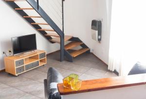a living room with a tv and a staircase at Rosario Suites in Rosario