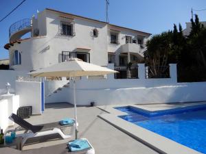 a white house with a swimming pool and an umbrella at Villa Amare in Benissa