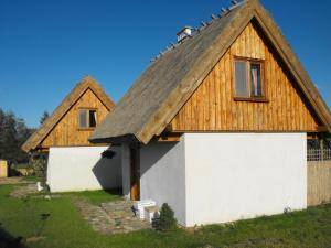 een huis met een rieten dak en een garage bij Domki przy lesie in Werblinia