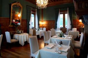 Hotel Castillo de Arteaga في Gautegiz Arteaga: غرفة طعام بطاولات بيضاء وكراسي وثريا