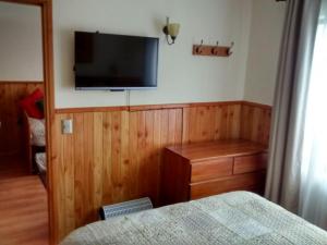 1 dormitorio con 1 cama y TV de pantalla plana en la pared en Depto Parque Suizo 800, en Pucón